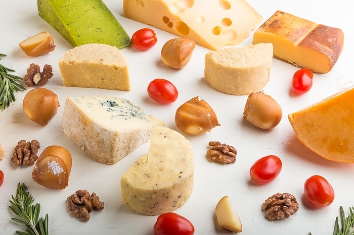 Set of different types of cheese with rosemary and tomatoes on a white wooden background. Side view, close up, by ULADZIMIR ZGURSKI
