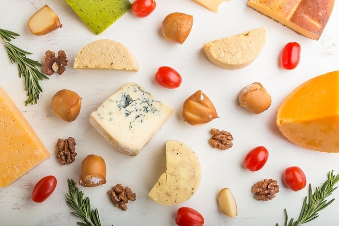 Set of different types of cheese with rosemary and tomatoes on a white wooden background. Top view, flat lay, close up, by ULADZIMIR ZGURSKI