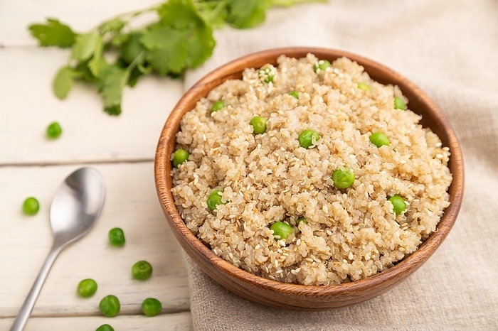 Quinoa porridge with green pea in wooden bowl on a white wooden background and linen textile. Side view, close up, selective focus, by ULADZIMIR ZGURSKI