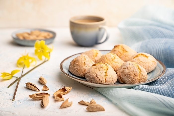 Almond cookies and a cup of coffee on a white concrete background and blue linen textile. Side view, close up, selective focus, by ULADZIMIR ZGURSKI