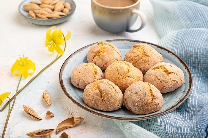 Almond cookies and a cup of coffee on a white concrete background and blue linen textile. Side view, close up, by ULADZIMIR ZGURSKI