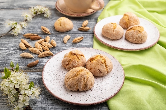 Almond cookies and a cup of coffee on a gray wooden background and green linen textile. Side view, close up, by ULADZIMIR ZGURSKI