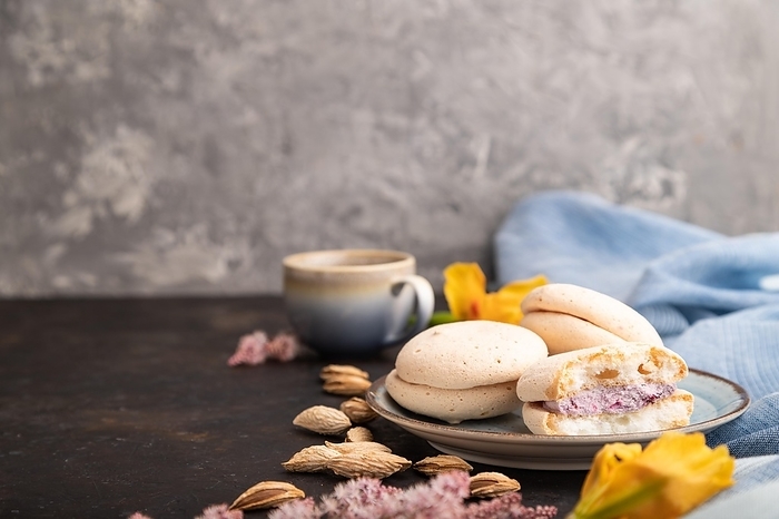 Meringues cakes with cup of coffee on a black concrete background and blue linen textile. Side view, copy space, selective focus, by ULADZIMIR ZGURSKI