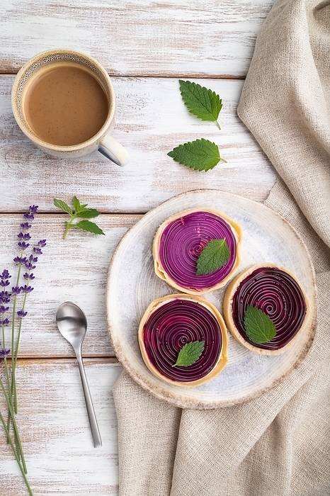 Sweet tartlets with jelly and milk cream with cup of coffee on a white wooden background and linen textile. top view, flat lay, close up, by ULADZIMIR ZGURSKI