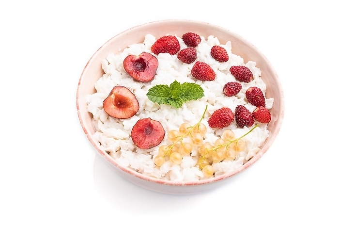 Rice flakes porridge with milk and strawberry in ceramic bowl isolated on white background. Side view, close up, by ULADZIMIR ZGURSKI