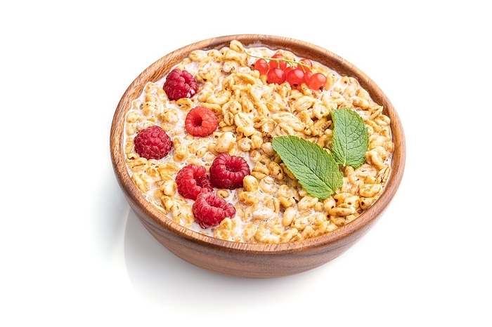 Wheat flakes porridge with milk, raspberry and currant in wooden bowl isolated on white background. Side view, close up, by ULADZIMIR ZGURSKI