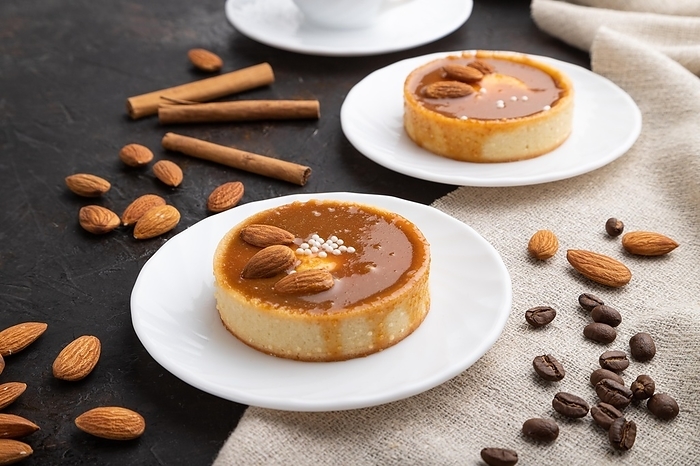 Sweet tartlets with almonds and caramel cream with cup of coffee on a black concrete background and linen textile. Side view, close up, by ULADZIMIR ZGURSKI