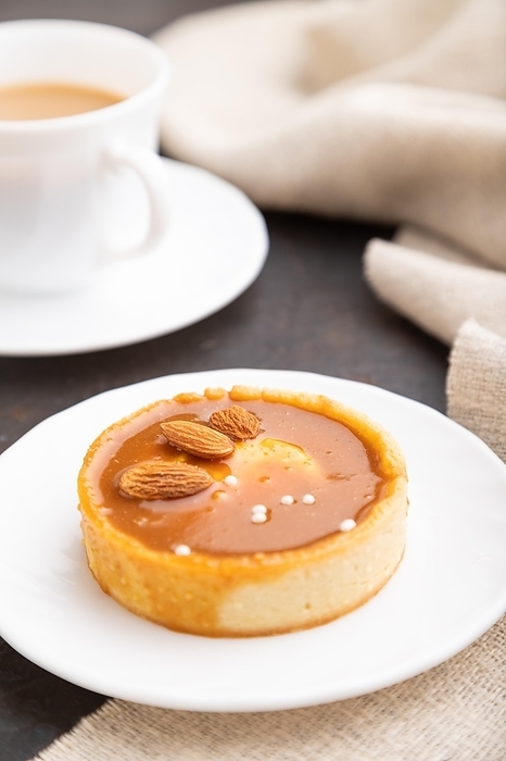 Sweet tartlets with almonds and caramel cream with cup of coffee on a black concrete background and linen textile. Side view, close up, selective focus, by ULADZIMIR ZGURSKI
