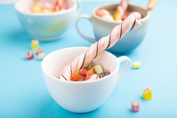 Heap of multicolored caramel candies in cups on blue pastel background. close up, side view, selective focus, by ULADZIMIR ZGURSKI