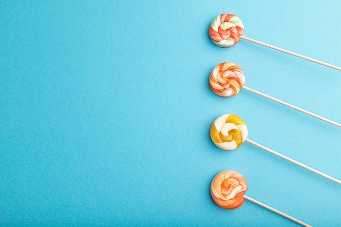Four lollipop candies on blue pastel background. copy space, top view, flat lay, by ULADZIMIR ZGURSKI