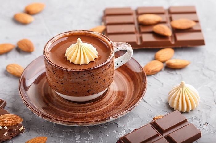 Cup of hot chocolate and pieces of milk chocolate with almonds on a gray concrete background. side view, close up, selective focus, by ULADZIMIR ZGURSKI