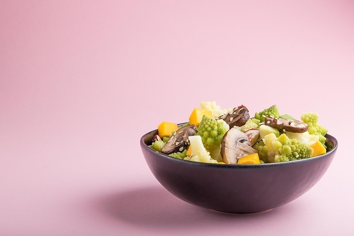 Vegetarian salad from romanesco cabbage, champignons, cranberry, avocado and pumpkin on a pastel pink background. side view, copy space, by ULADZIMIR ZGURSKI