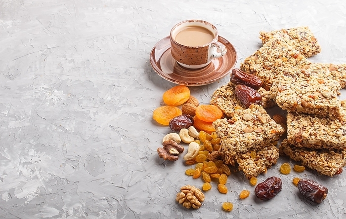 Homemade granola from oat flakes, dates, dried apricots, raisins, nuts with a cup of coffee on a gray concrete background. Side view, copy space, by ULADZIMIR ZGURSKI