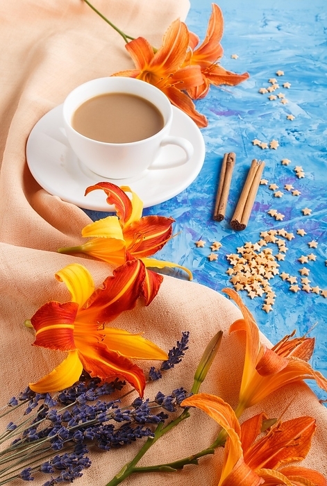 Orange day-lily and lavender flowers and a cup of coffee on a blue concrete background, with orange textile. Morninig, spring, fashion composition. side view, by ULADZIMIR ZGURSKI