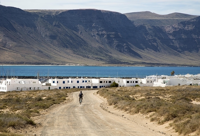 Spain Cyclist dirt track leading to Caleta de Sebo village on Graciosa island, Lanzarote, Canary Islands, Spain, Europe, by Ian Murray