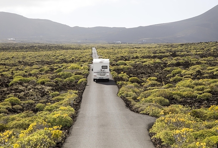 Spain Motorhome on straight sealed tarmac road crossing lava flows Malpais de Corona, Lanzarote, Canary Islands, Spain, Europe, by Ian Murray