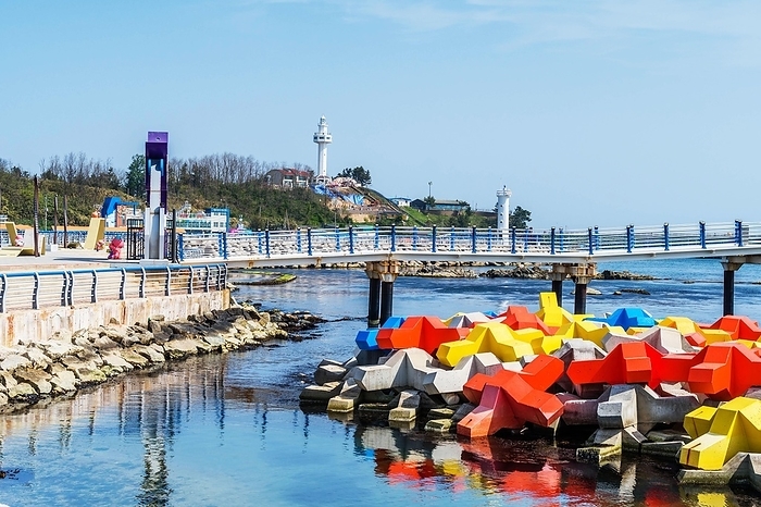 Korea Colorful breakwater blocks in ocean water with lighthouse on hill in background in Goseong, South Korea, Asia, by aminkorea