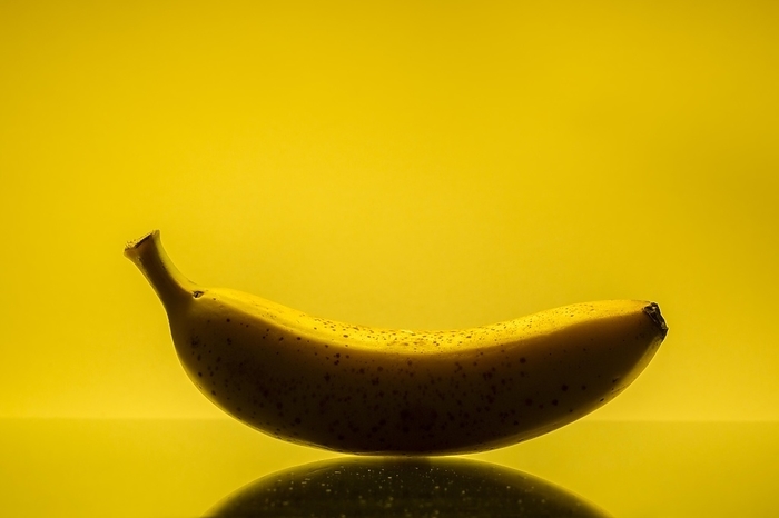Banana against yellow background, by alimdi / Arterra / Johan De Meester