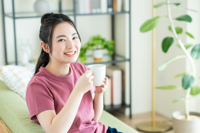 Young Japanese woman drinking coffee in the living room (People)