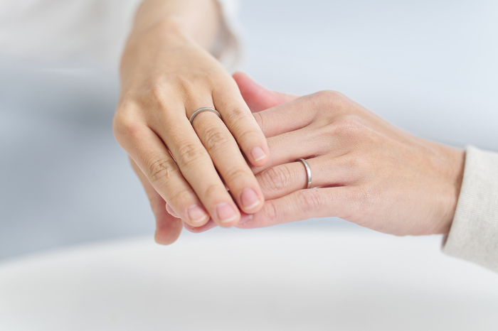 A couple showing their wedding rings with their hands on top of each other.
