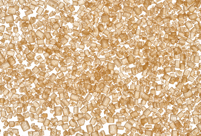 Brown cane sugar granules on isolated background, top view Brown cane sugar granules on isolated background, top view