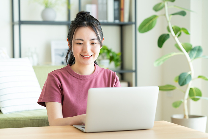 Young Japanese woman on computer in living room (People)