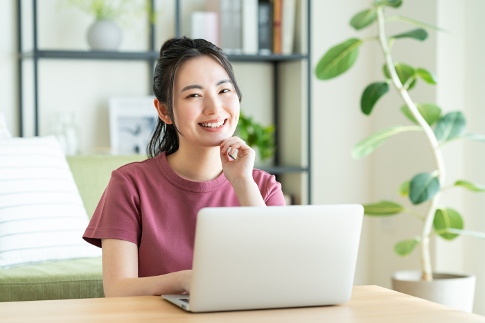 Young Japanese woman on computer in living room (People)