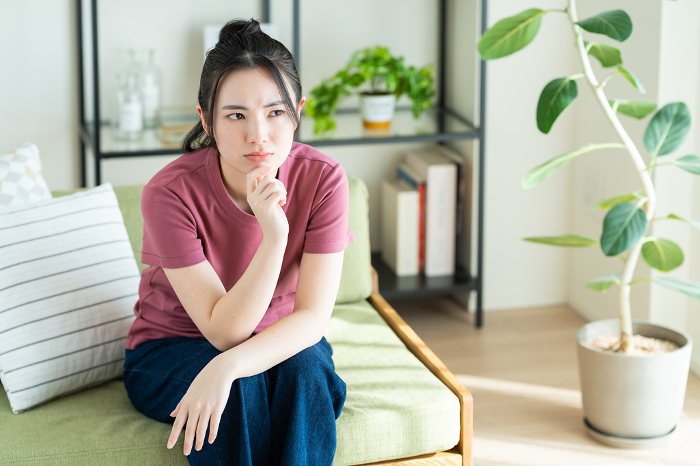 Young Japanese woman distressed in her living room.