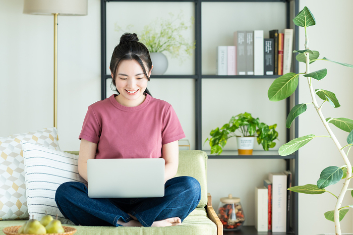 Young Japanese woman using computer in living room (People)