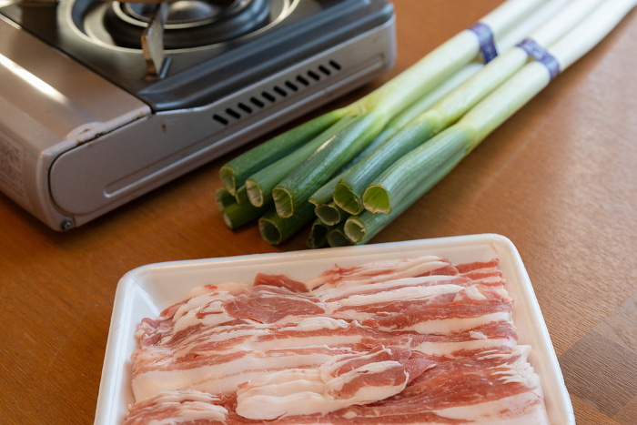 Pork shabu-shabu set on the table Sliced black pork, green onions and cassette stove