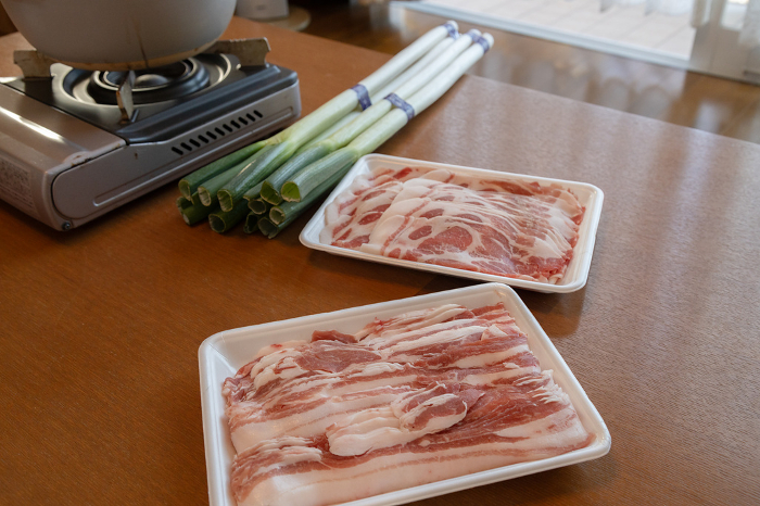 Pork shabu-shabu set on the table Sliced black pork, green onions and cassette stove