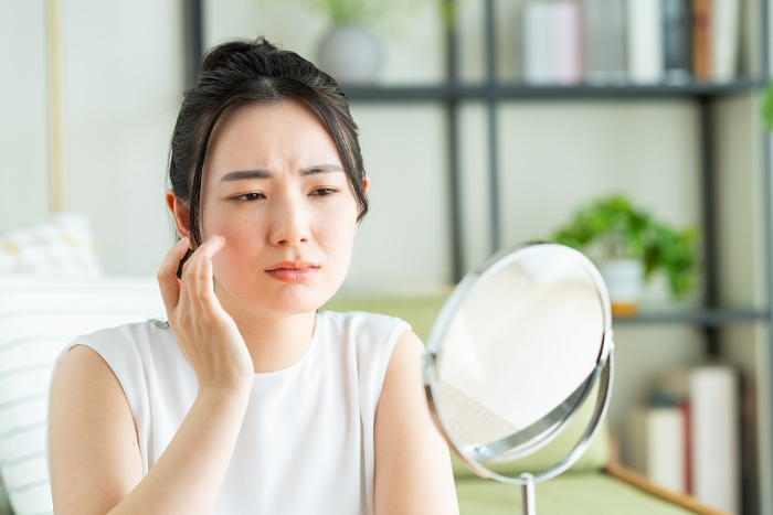 A young Japanese woman struggling with skin care (People)