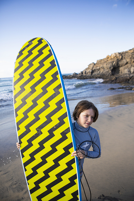 10 year old boy with surf board, Mexican Baja Mexico, Baja, Pescadero, Boy carrying surfboard on beach