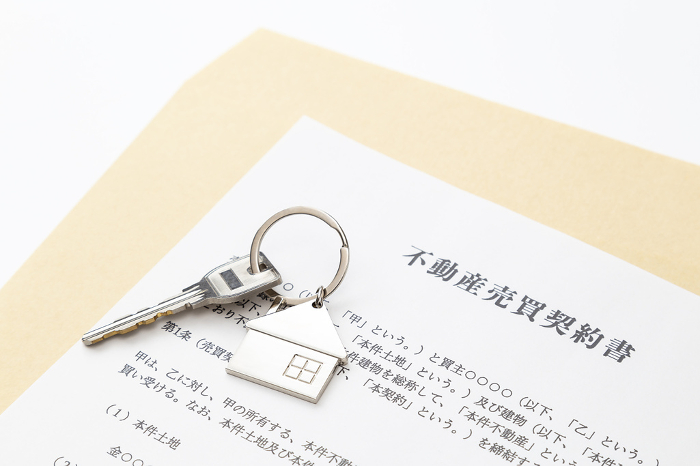 Real estate sales contract and keys on white background