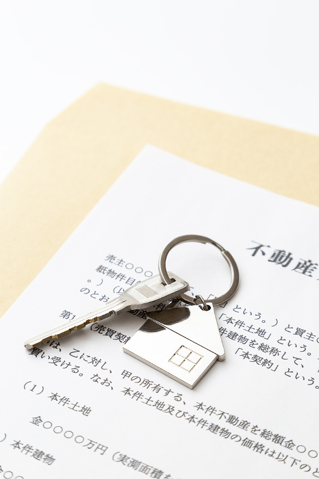 Real estate sales contract and keys on white background