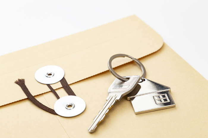 Envelope with string and house key on white background