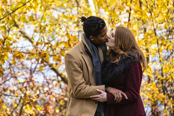 LJMZZ41642  Stevon Artis ,LJMZZ41643  Kayla Kimo  A mixed race married couple hugging and kissing each other while spending quality time together during a fall family outing in a city park  Edmonton, Alberta, Canada, by LJM Photo   Design Pics