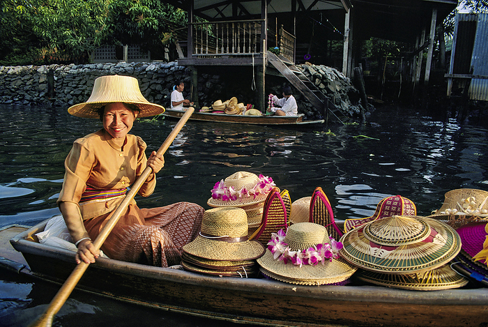NA Smiling Thai woman with a canoe full of straw hats  Damnoen Saduak, Thailand, by Michael Melford   Design Pics