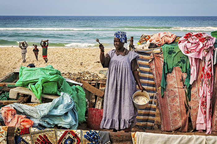 NA Woman prepared food surrounded by colourful cloth in the beach settlement Saint Louis, Senegal. The town was once an important economic center during French West Africa, however, it still has important industries, including tourism, a commercial center, a center of sugar production, and fishing  Saint Louis, Senegal, by Randy Olson   Design Pics