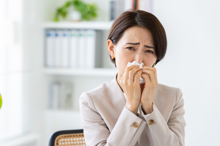 Middle Japanese businesswoman suffering from hay fever at office (Female / People)