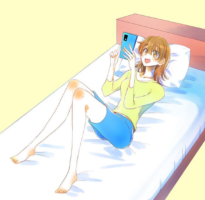 Woman laughing at her phone on the bed