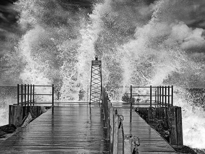 Black and white image of lighthouse in swell with splashing waves on Danish North Sea coast of Vorup Black and white image of lighthouse in swell with splashing waves on Danish North Sea coast of Vorup, by Zoonar Katrin May