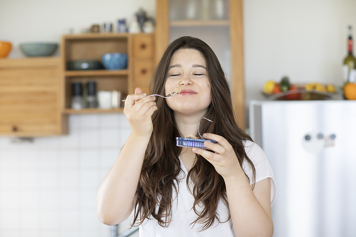 young woman eating sardines at home