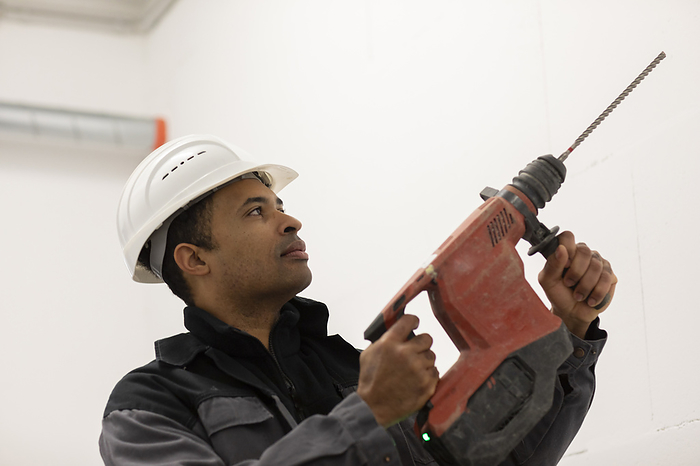 Engineer with helmet, portrait with a drill