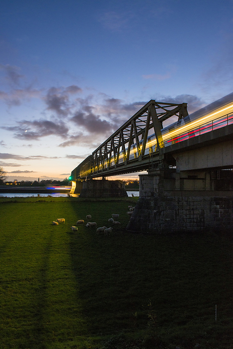 High speed train passing over a bridge as the sunsets. light trails