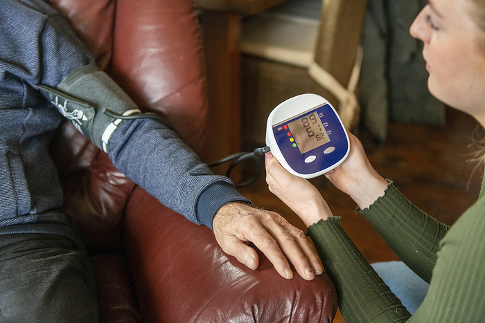 Thuiswonende ouderen Assisted living nurse taking elderly mans blood pressure with mobile medical device