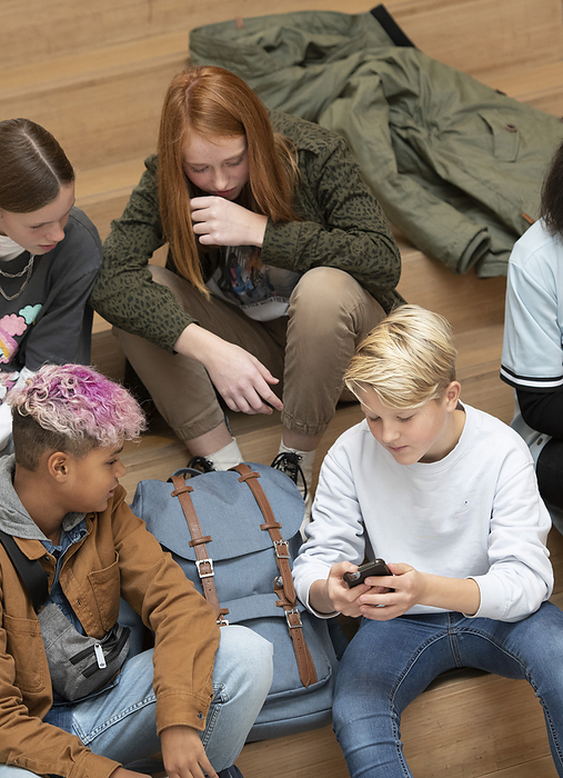 Voortgezet onderwijs Group of young teenagers bonding at school, while looking at their phones