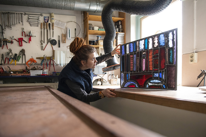 Glazenier aan het werk apprentice glass maker, stained glass craftman inspecting herwork