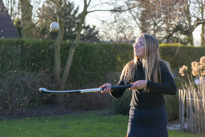 Hockey meisje Teenage blonde sttractive young lady practising hockey ball skills in her garden at sunset