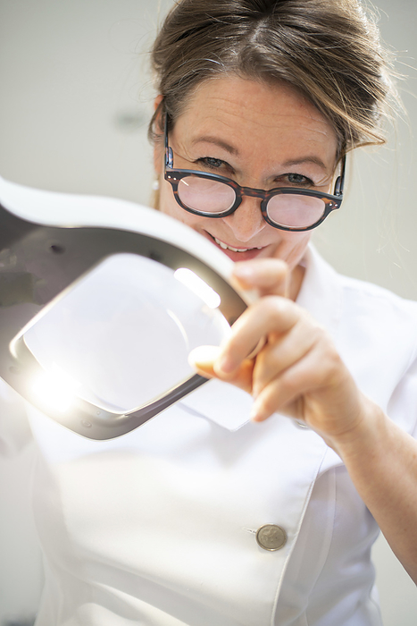 beroep schoonheidsspecialiste portrait of brunette beautician looking through a magnifying glass at her patient